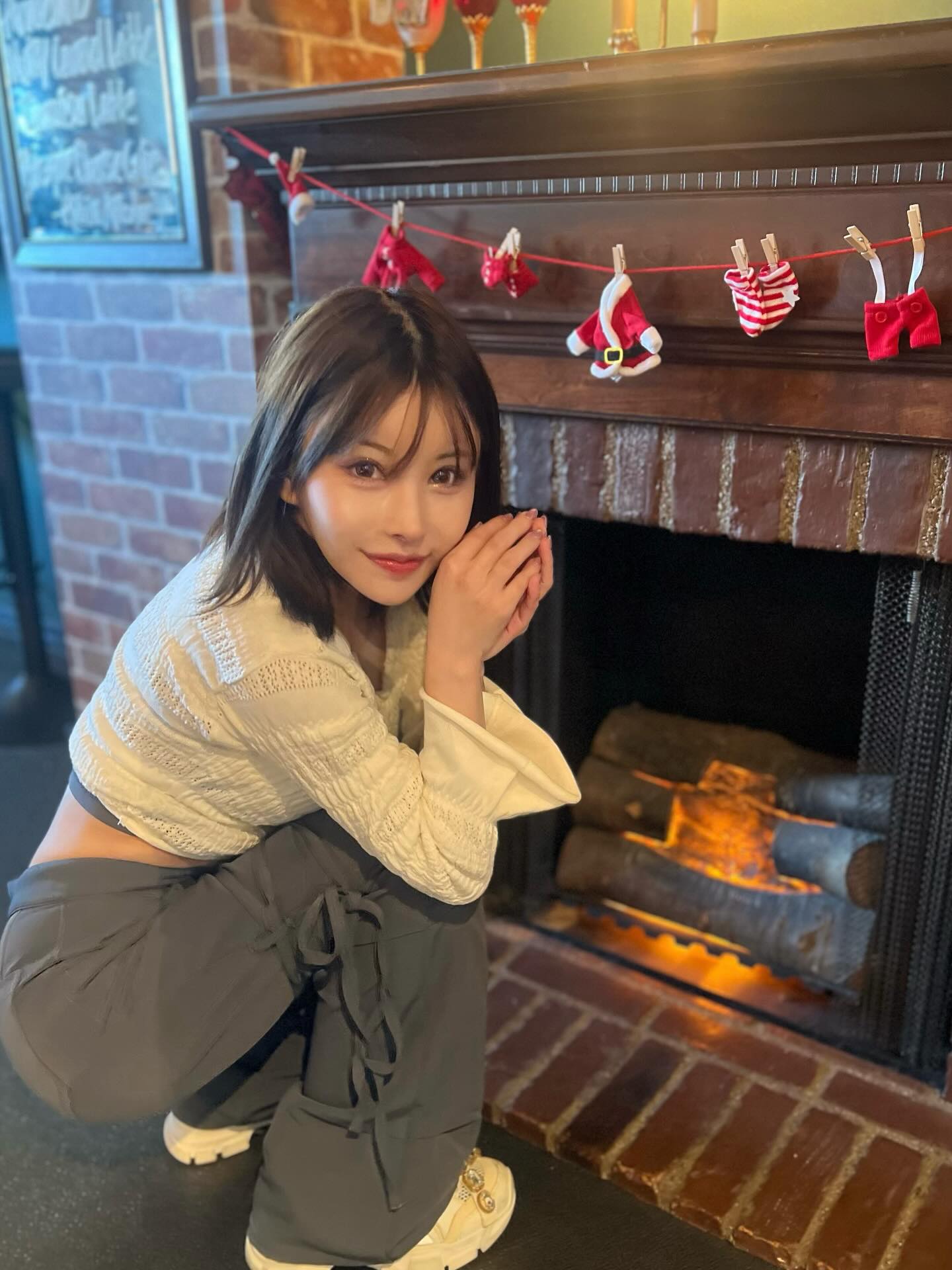Rena seated by a fireplace
